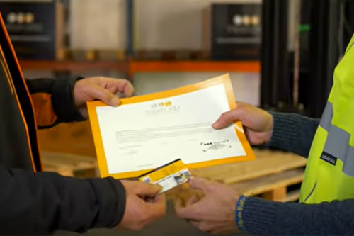 Formador facilitando al alumno el diploma y la acreditación tamaño carnet de la realización del curso de carretillero trekform